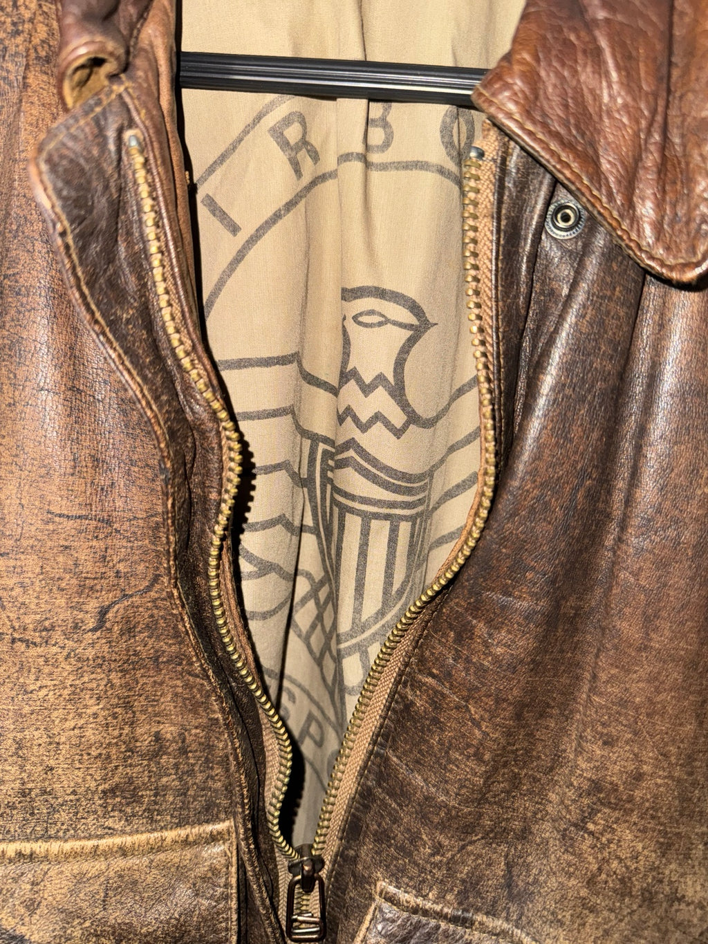 Distressed brown leather bomber jacket zipper and lining detail