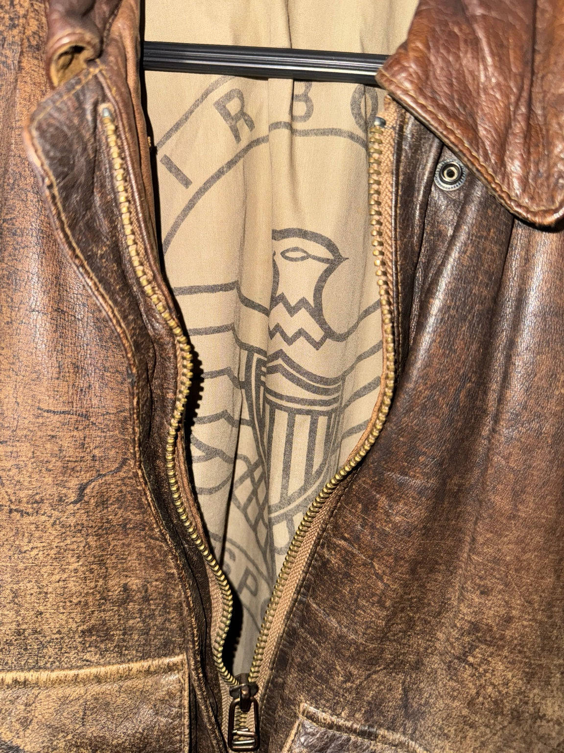 Distressed brown leather bomber jacket zipper and lining detail